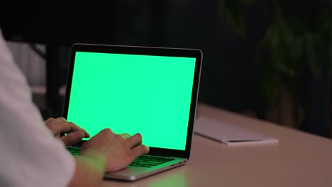 people using green screen laptop computer on table in office at night