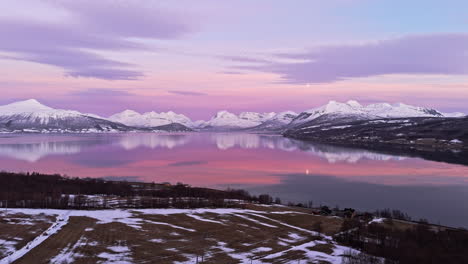 snowy fjords in tromsø at sunrise, pink sky reflecting on calm waters, serene view