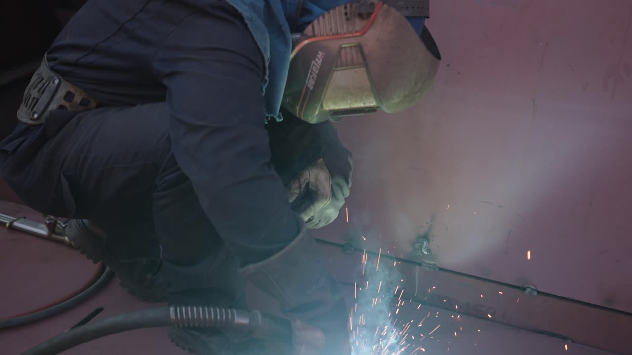 Masked man repairing a ship with welding machine
