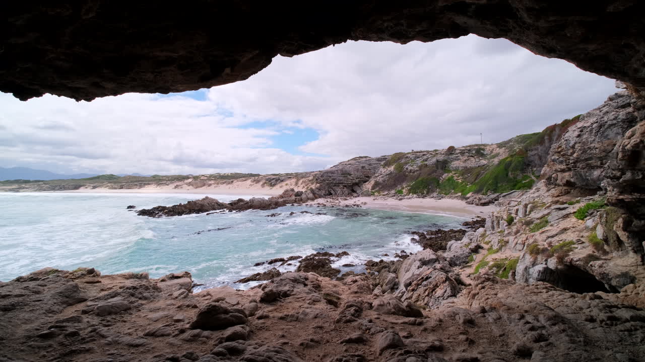 View from inside dark Klipgat Cave over ocean and beach in Walker Bay reserve
