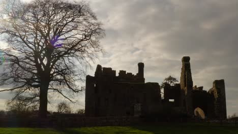 Establishing-shot-of-Bective-Abbey,-low-orbit-backlit-by-sun-with-building-silhouette-of-Irish-heritage