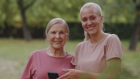 portrait of joyous female trainer and senior woman outdoors