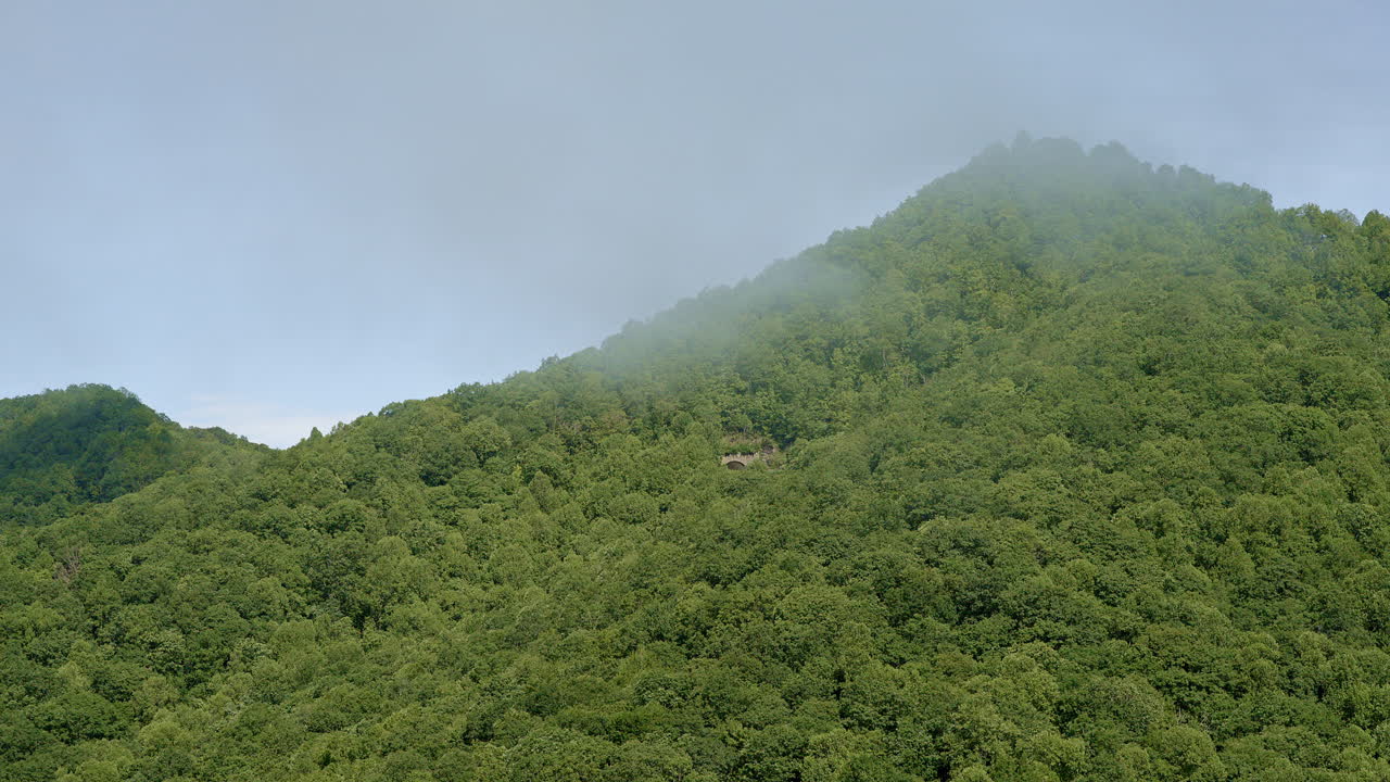 Drone flying into clouds veiling mountain ridges