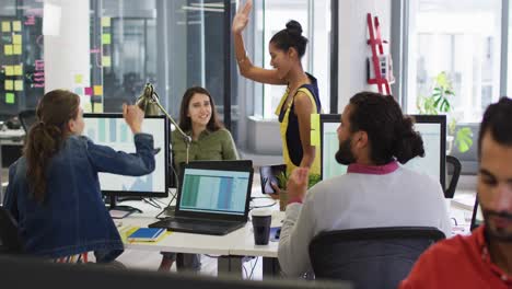 Diverse-group-of-work-colleagues-giving-high-five-and-smiling