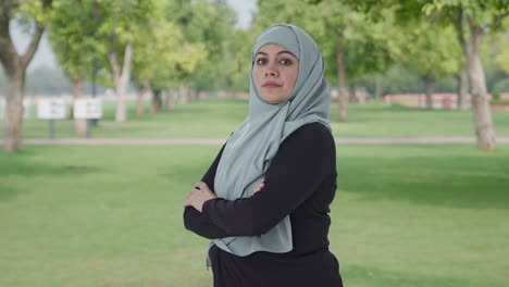 portrait of confident muslim woman standing crossed hands in park