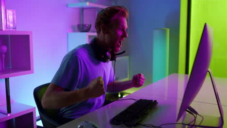 Cyber-game-winner-enjoying-success-in-neon-room.-Excited-student-rest-on-weekend