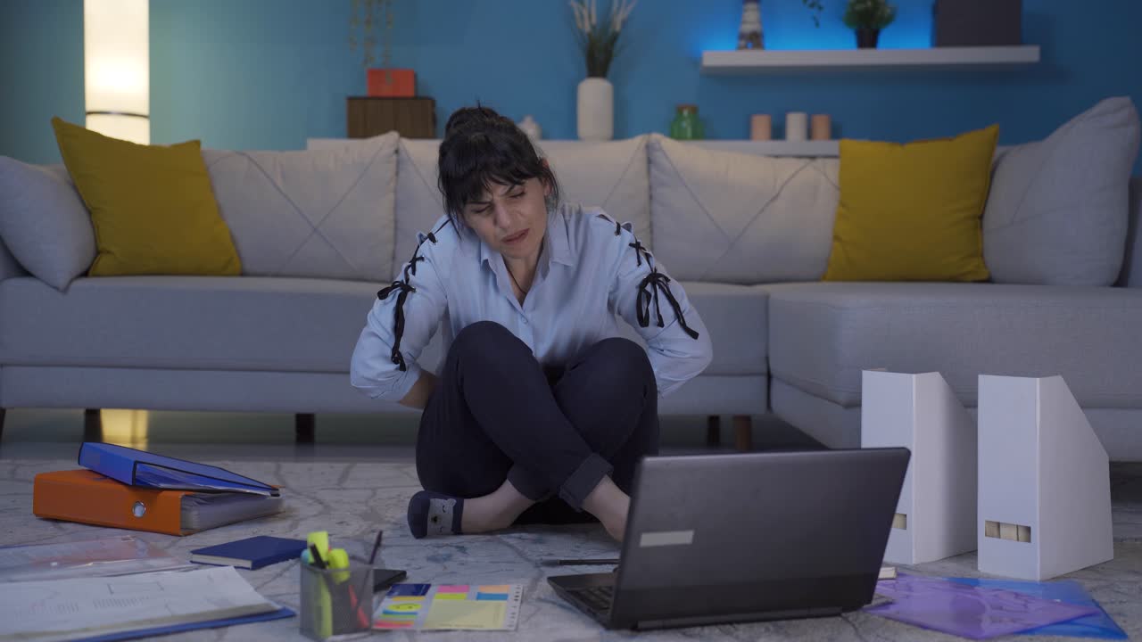 una mujer que trabaja en una oficina en casa tiene dolor de estómago.