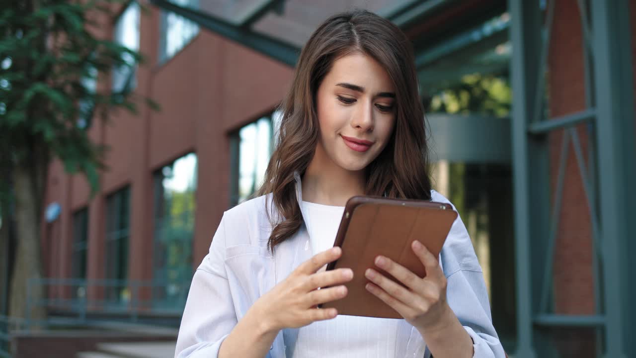 cámara haciendo zoom en una estudiante caucásica usando una tableta en la calle