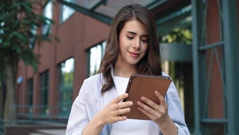 camera zooming on a caucasian student woman using a tablet in the street