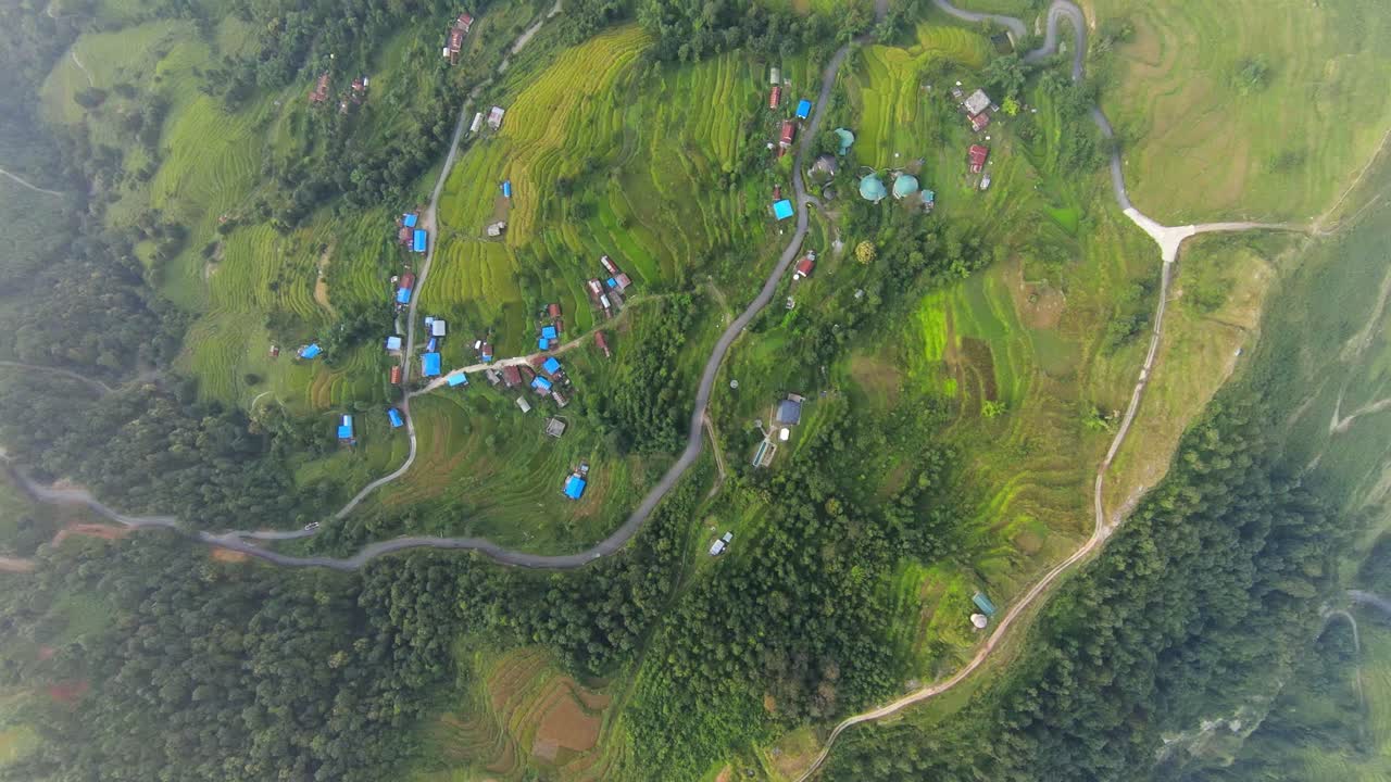 panorámica de drones de arriba hacia abajo visión general de las tierras de cultivo rurales del pueblo con campos en terrazas y techos azules brillantes, niebla de niebla