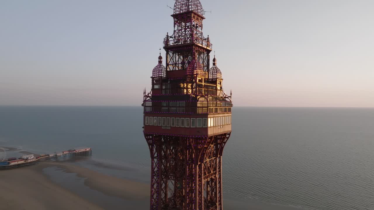 Blackpool Tower observation deck level and Central pier at golden hour with calm sea. Lancashire, UK.