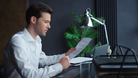 businessman looking at graphics on document. freelancer working on laptop