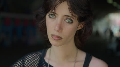 close up outdoor fashion portrait of young alternative style woman standing in underpass in london city street uk in real time