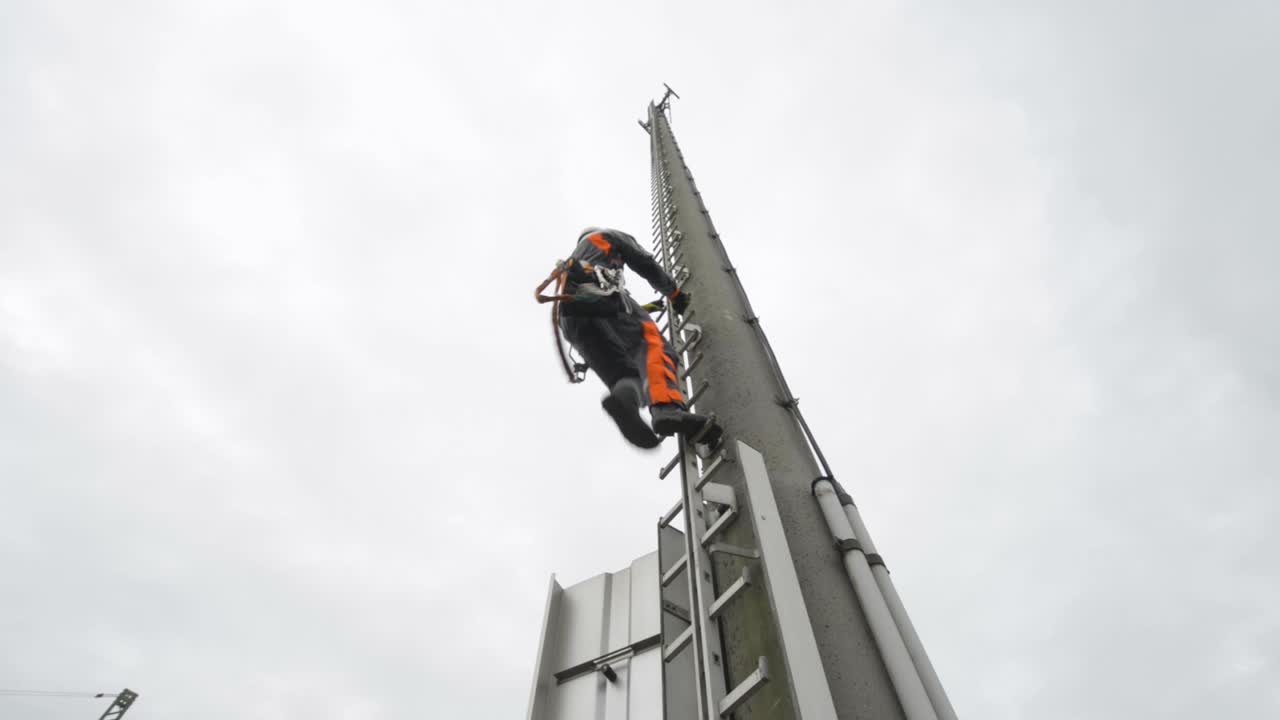 Worker climbing a telecommunication tower with safety harness