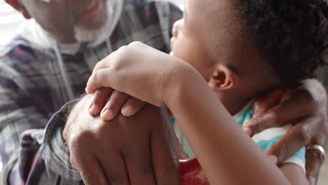 african american grandfather and grandson stacking hands, embracing at home, slow motion