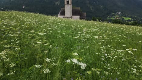 wonderful church in a valley on a green meadow with high mountains in the background, dolomites, italy, europe, drone