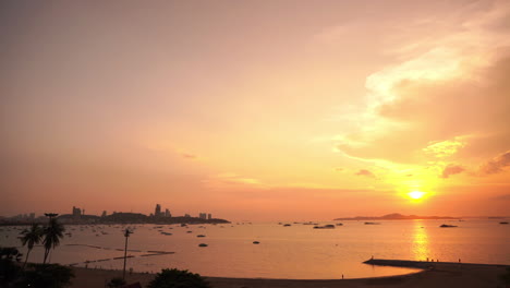 gorgeous seascape with the sun setting to the right of a large city skyline