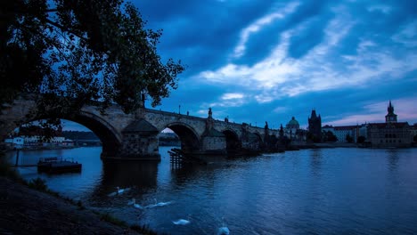 Blue-morning-cloudy-timelapse-of-the-Charles-Bridge-in-Prague,-Czech-Republic-next-to-the-Vltava-river-with-wide-angle-panoramic-view