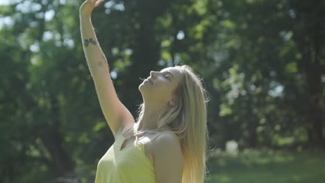 mujer con vestido amarillo bailando con gracia en el parque de verano