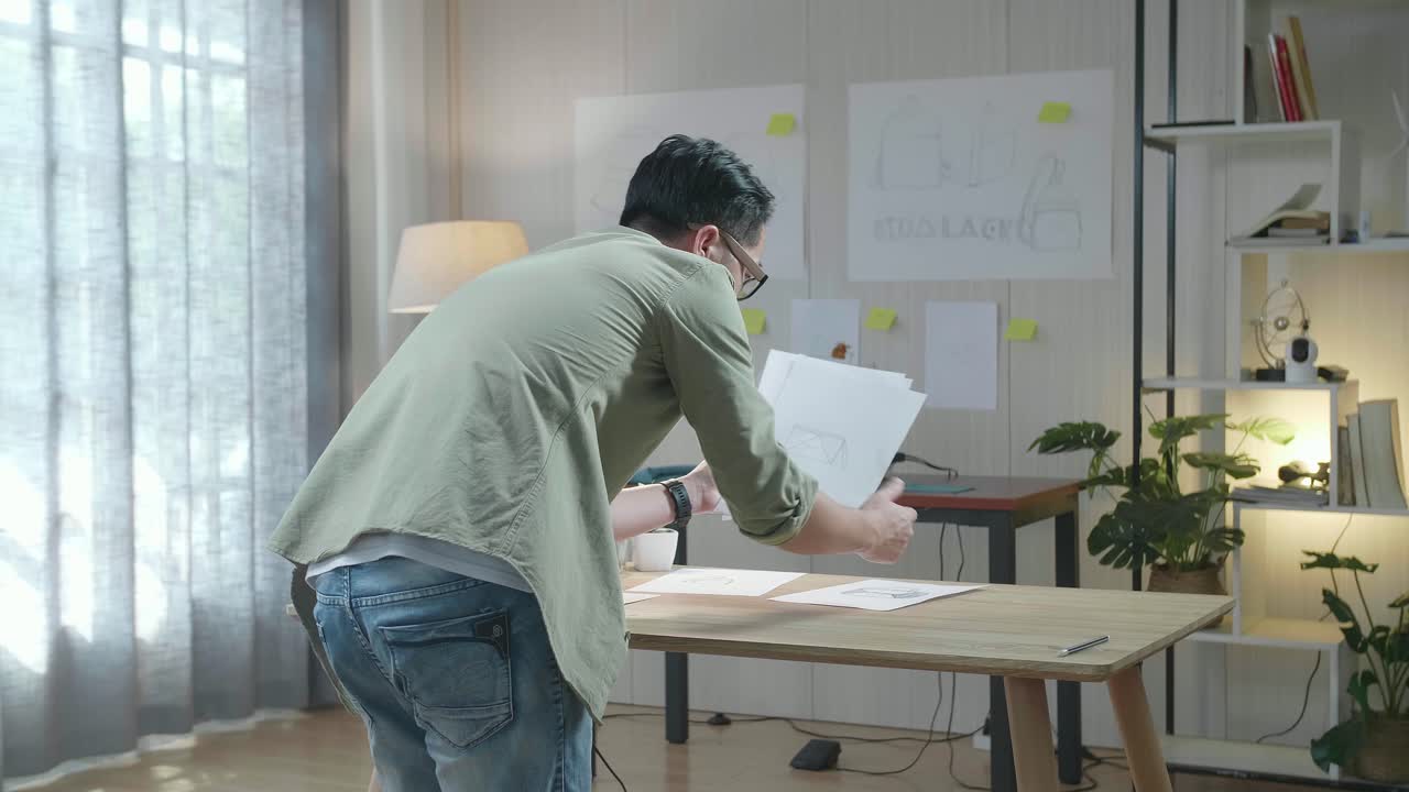 사무실에서 배그 스케치 레이아웃을 배치하는 남자 디자이너의 뒷면