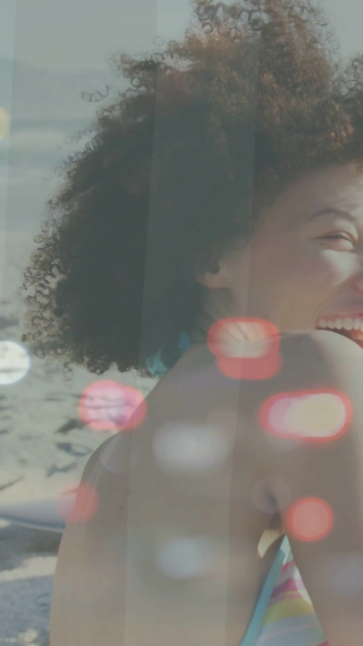 Vertical video: Woman turning to offscreen call on beach, laughing, showing strap, bokeh for travel