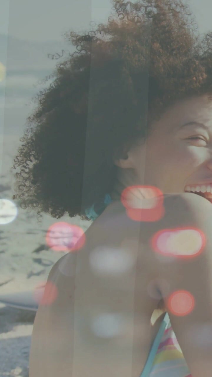 Vertical video: Woman turning to offscreen call on beach, laughing, showing strap, bokeh for travel