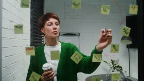 young woman is engaged in planning using glass board working alone in office