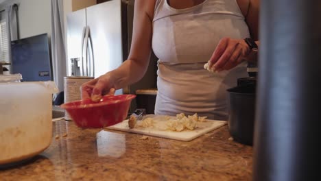 woman home cooking putting batter mix on chopped cauliflower pieces