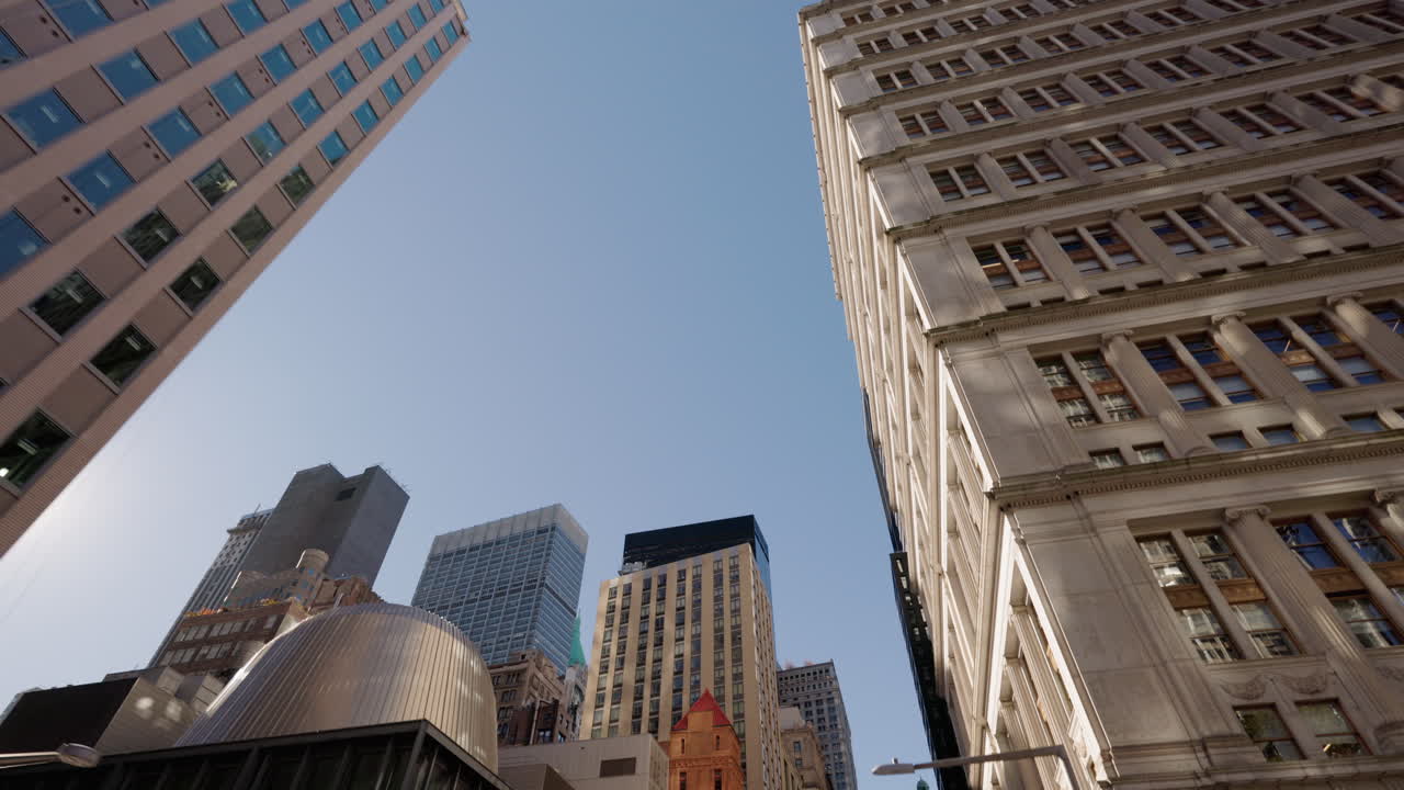 Vista dal basso di edifici di New York City con architettura classica e moderna sotto un cielo blu limpido.