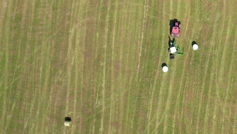 agricultural tractor wrapping round hay bale with white plastic cling wrap at the farm