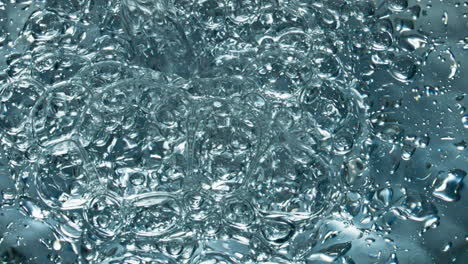 small air bubbles rising up to water surface closeup. drink filling glassware