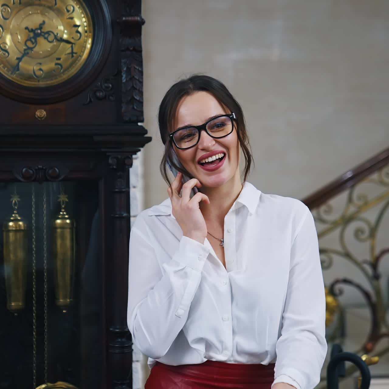 Bella signora nella hall dell'hotel. Giovane donna graziosa in abiti eleganti e occhiali con un telefono che canta nell'hotel di lusso