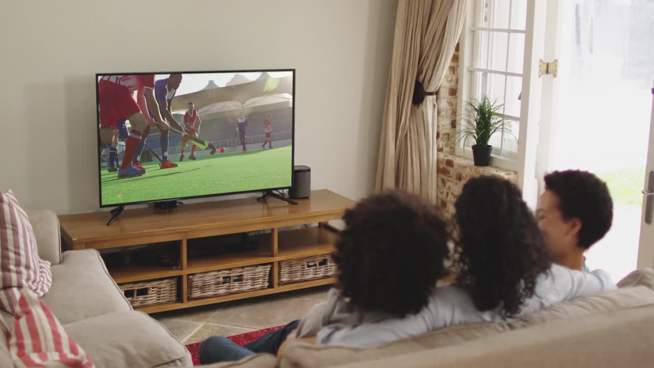Famiglia felice seduta a casa insieme che guarda una partita di hockey in TV