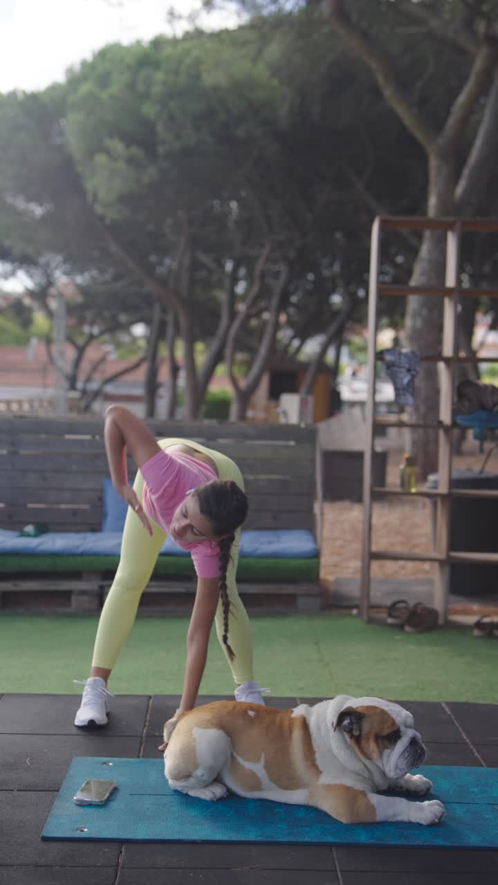 Woman Stretching Outdoors with Her Bulldog Companion