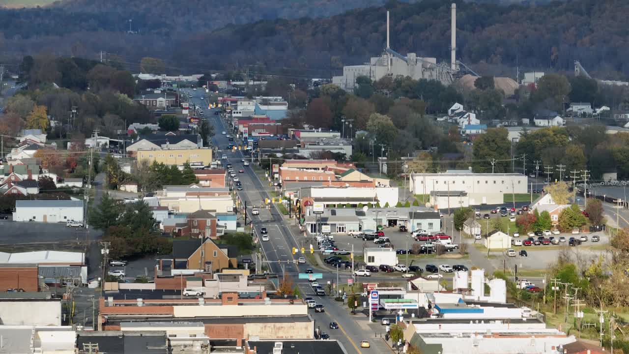 Aerial wide shot of driving cars on Bridge in american town, Main street with Railroad in autumn season. Mc Donalds Restaurant and housing area in Virginia. Zoom tilt up.