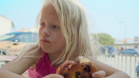 adorable little girl enjoying a delicious pastry outdoors