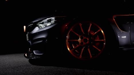 detail shot of the front golden wheel with low profile tires of a sports car at night