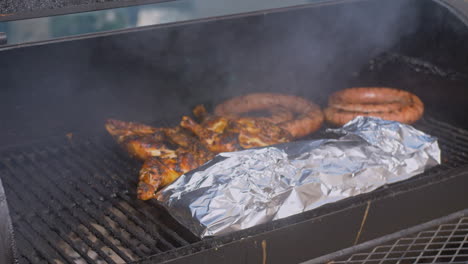 man puts foil wrapped ribs on to smoking bbq pit