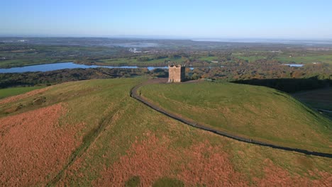 stone tower on hilltop bathed in morning light with hillwalker and slow orbit