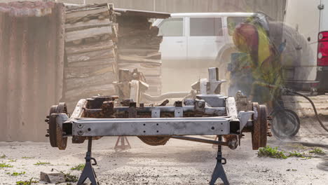 Repairman-working-on-Old-Car-Chassis,-Sandblasting-the-damaged-steel,-Static-Time-lapse