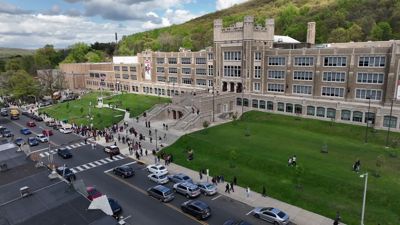 Aerial view of a bustling school campus with students and cars