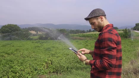 Farmer-using-tablet-looks-at-his-field.