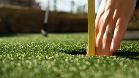 senhora jogando golfe em miniatura afundando um putt