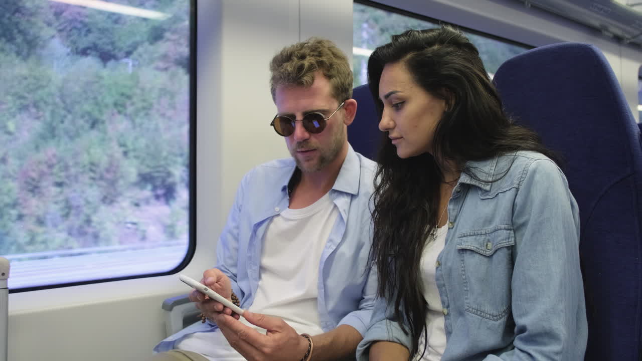 una pareja mirando un teléfono inteligente en un tren
