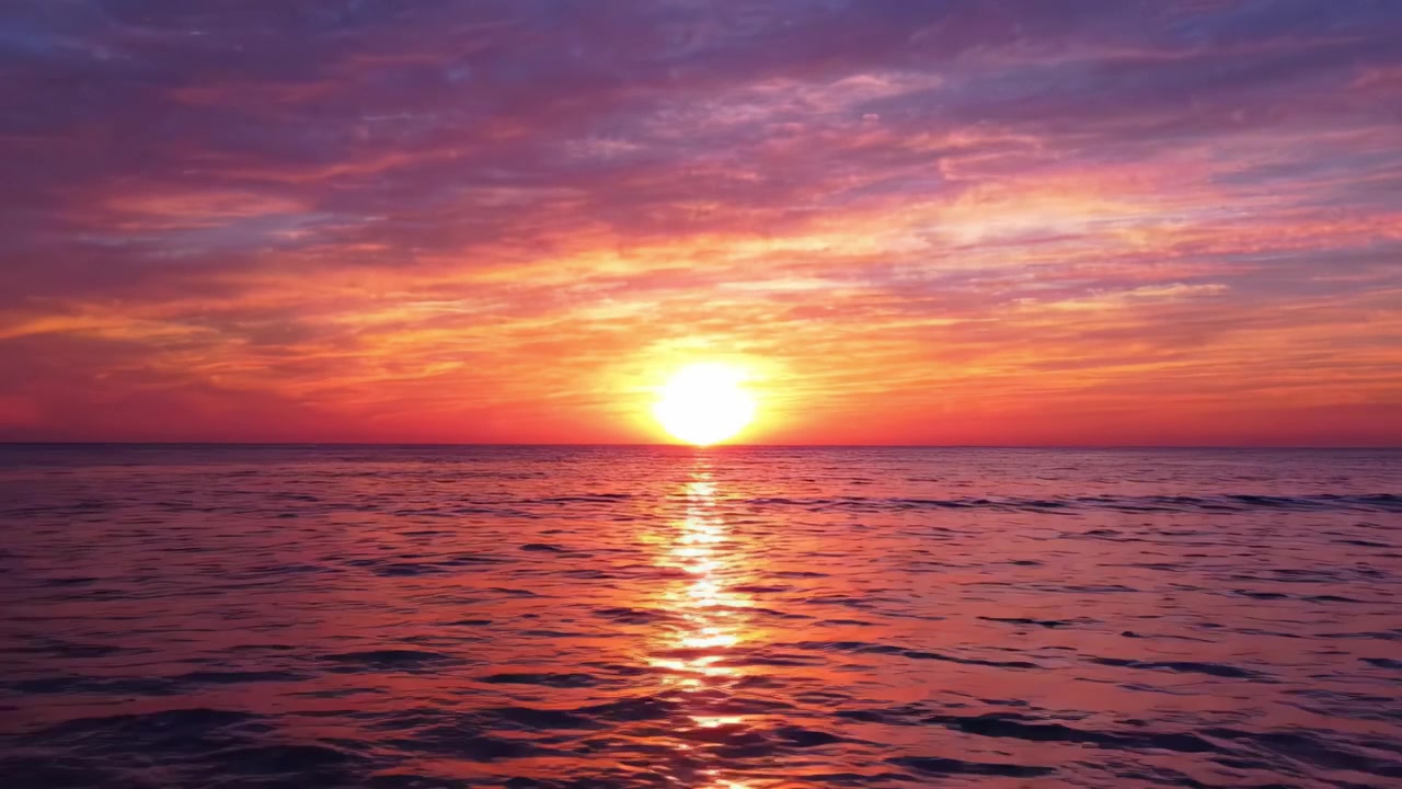 Ein atemberaubender Sonnenuntergang taucht den ruhigen Ozean in lebendige Farbtöne und fängt die friedliche Schönheit der Natur ein, während die Sonne in einem spektakulären Farbenspiel unter dem Horizont versinkt