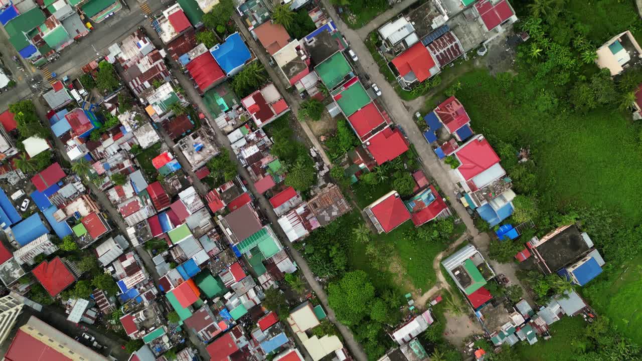 Aerial top-down view of dense residential neighborhood in Naga City, Philippines with colorful rooftops, streets, and lush greenery