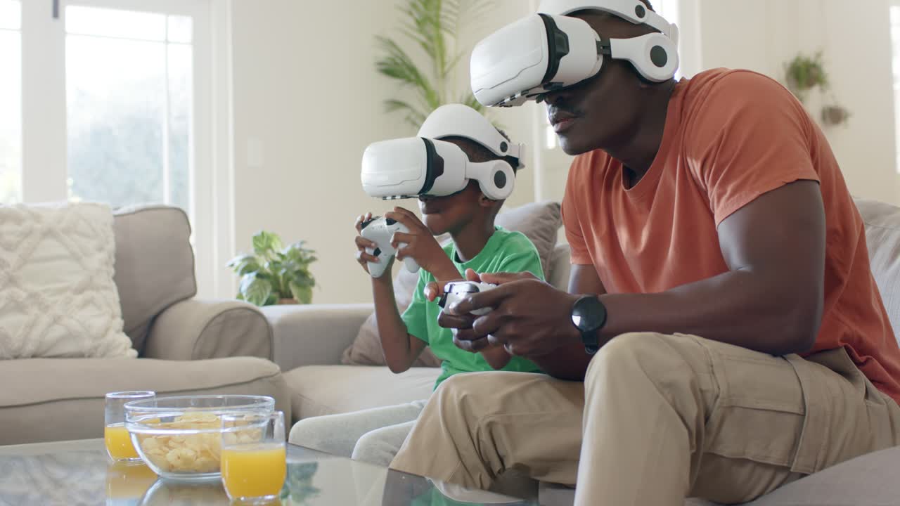 Mentre il gioco sta per iniziare, padre e figlio sono appoggiati al divano, tengono i controller e giocano a un gioco in VR.