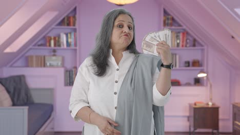 confident indian mother using money as fan