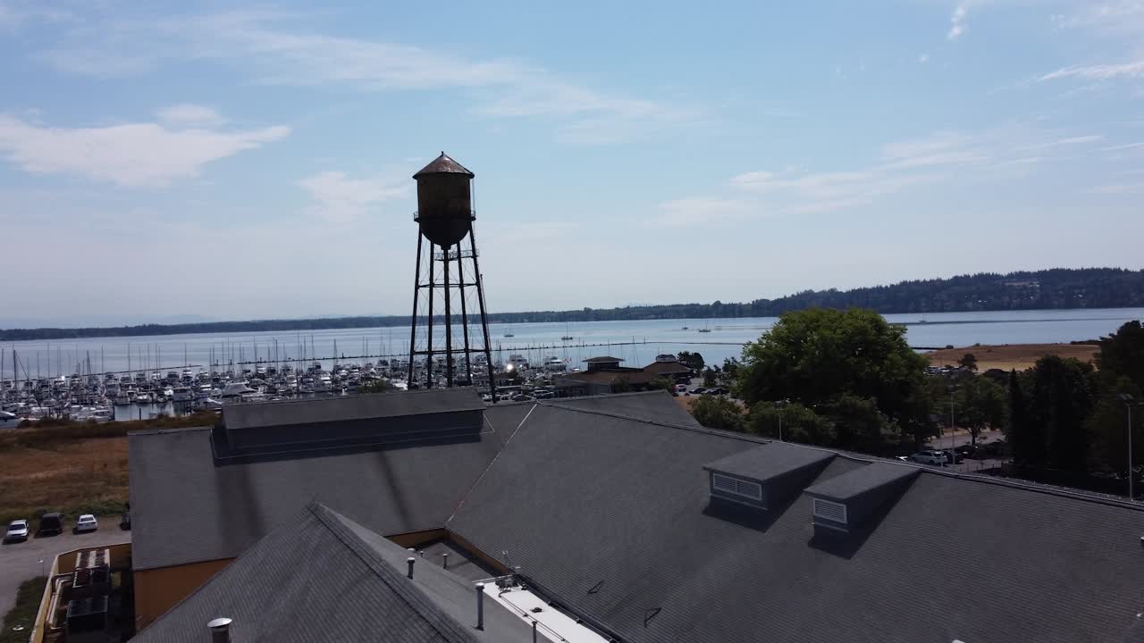 Aerial drone view of Semiahmoo, Washington harbor with boats on calm sea, scenic shoreline, and iconic water tower