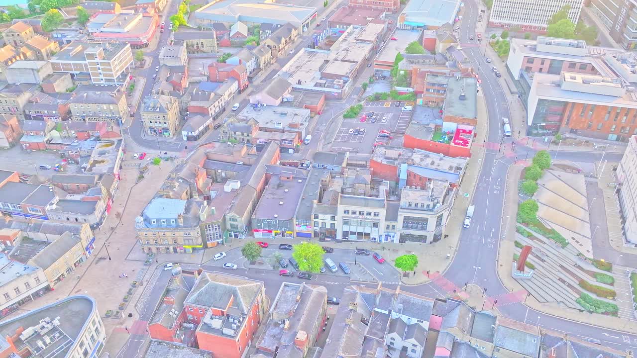 Aerial top-down view of Barnsley town centre showing dense rooftops, local shops, car parks, and road layout near the Civic and Alhambra precincts, captured during golden hour